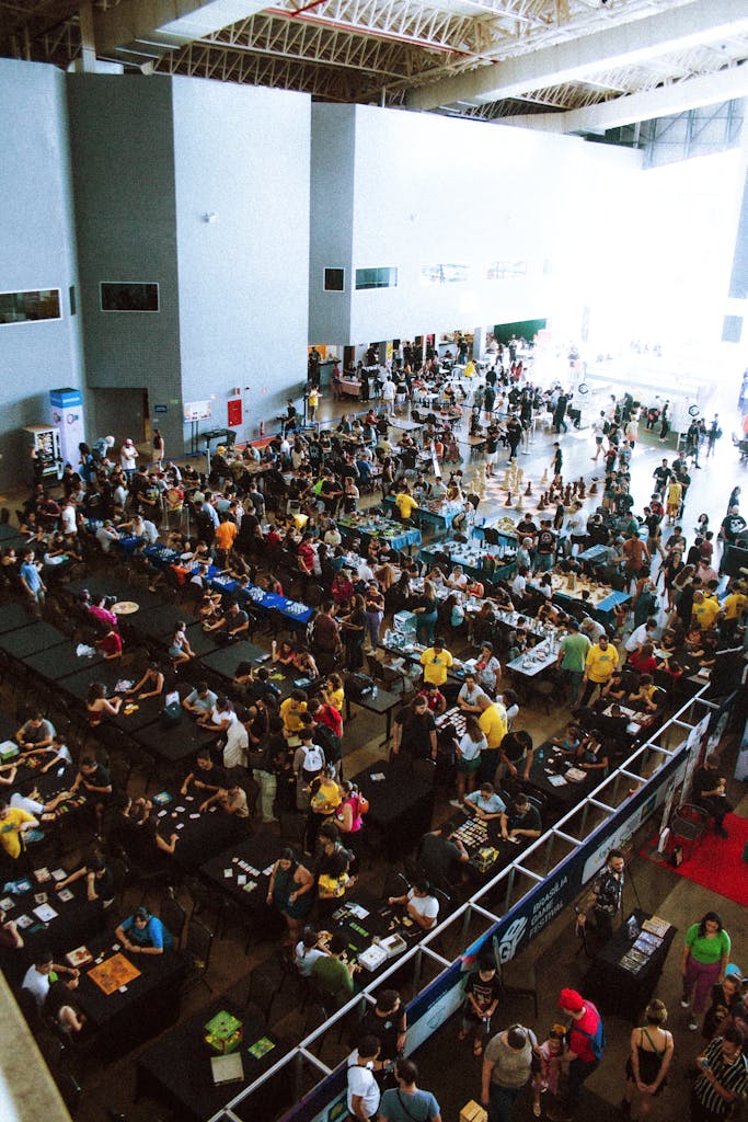 A bustling convention center filled with attendees at tables and walkways.