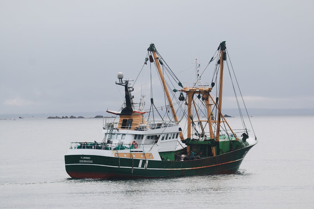 A large industrial trawler navigating calm seas on an overcast day.