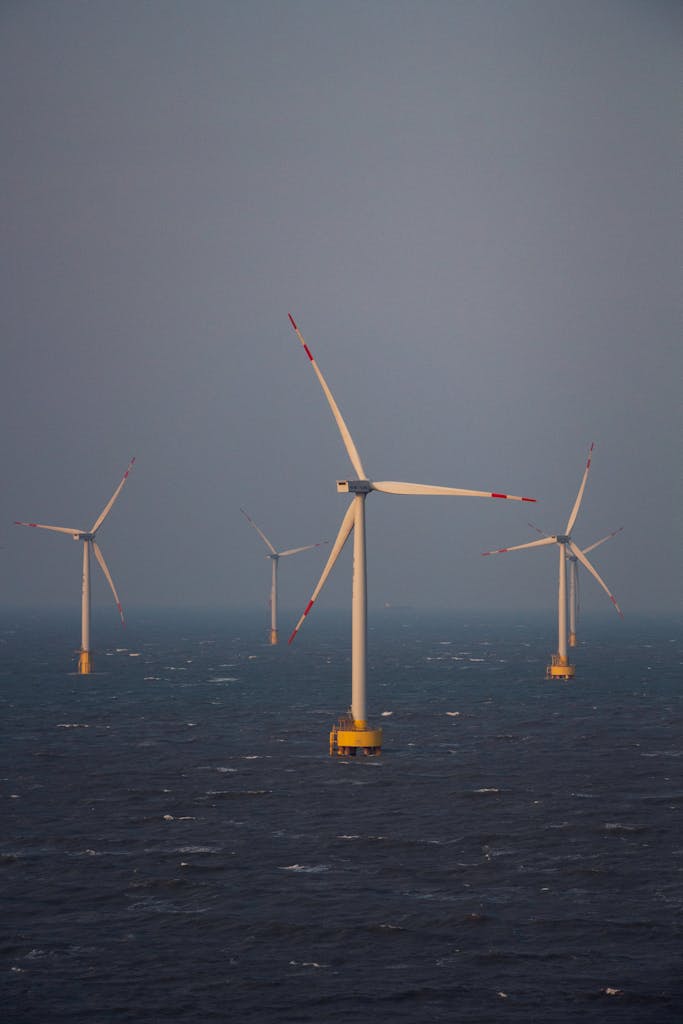 A series of wind turbines in the ocean generating clean energy at twilight.