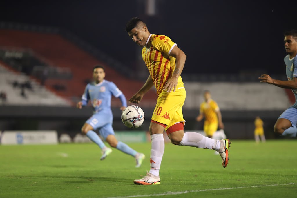 Soccer players in action during a competitive night match on a well-lit football field.