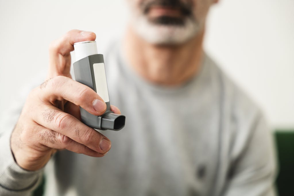 Man using an inhaler for respiratory health indoors.