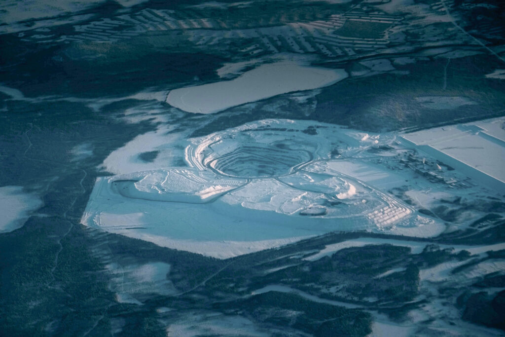 Picturesque drone view of rocky steps at open pit mine covered with snow in industrial terrain in evening