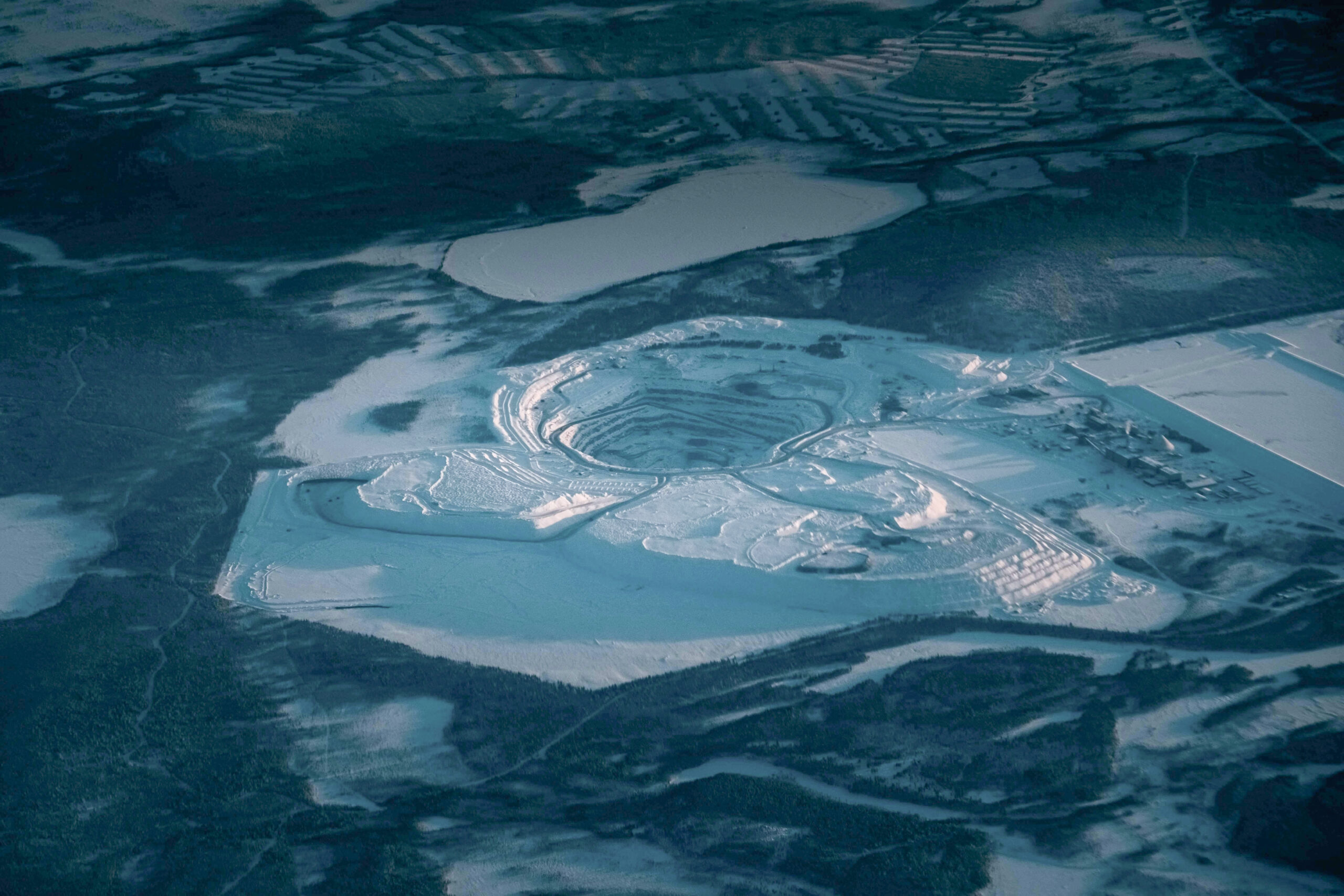 Picturesque drone view of rocky steps at open pit mine covered with snow in industrial terrain in evening